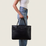 Model carrying the Alessia Large Tote in black nappa leather by its top handles