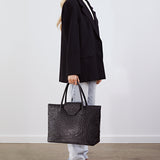 Model holding the Alessia Large Tote in black ostrich by its top handles