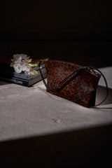 Blake Large Clutch in cheetah print calf hair resting on a table in a softly lit, dark interior