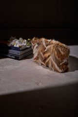 Blake Large Clutch in multicolor fox fur resting on a table in a softly lit, dark interior