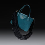 Bottle green suede tote with the black nappa Fringe Shoulder Strap against a dark background