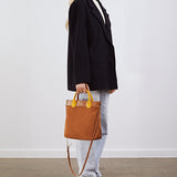 Model holding the Kelly Medium Shopper in tan suede by its top handles