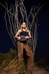 Model standing in front of bare branches at night with the Taylor Mini Clutch in black ostrich