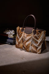 Alessia Large Tote in multicolor fox fur resting on a table in a softly lit, dark interior