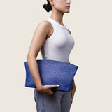 Model holding the Blake Large Clutch in blue ostrich at her side