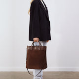Model holding the Gisele Large Shopper in brown suede by its top handles