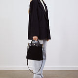 Model holding the Kelly Medium Shopper in black suede by its top handles