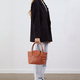 Model holding the Lucille Mini Tote in tan ostrich by its top handles