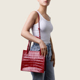 Model wearing the Molly Mini Book Tote in cherry red alligator on the shoulder